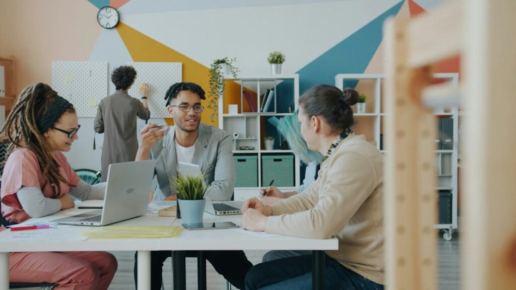 Marketing team discussing a campaign around a table with laptops in a modern office