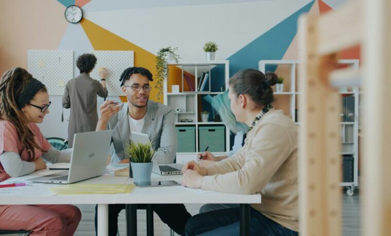 Marketing team discussing a campaign around a table with laptops in a modern office