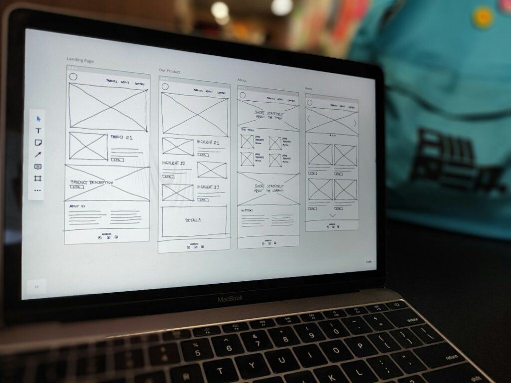 Designer sketching a landing page layout next to a laptop showing a website mock-up
