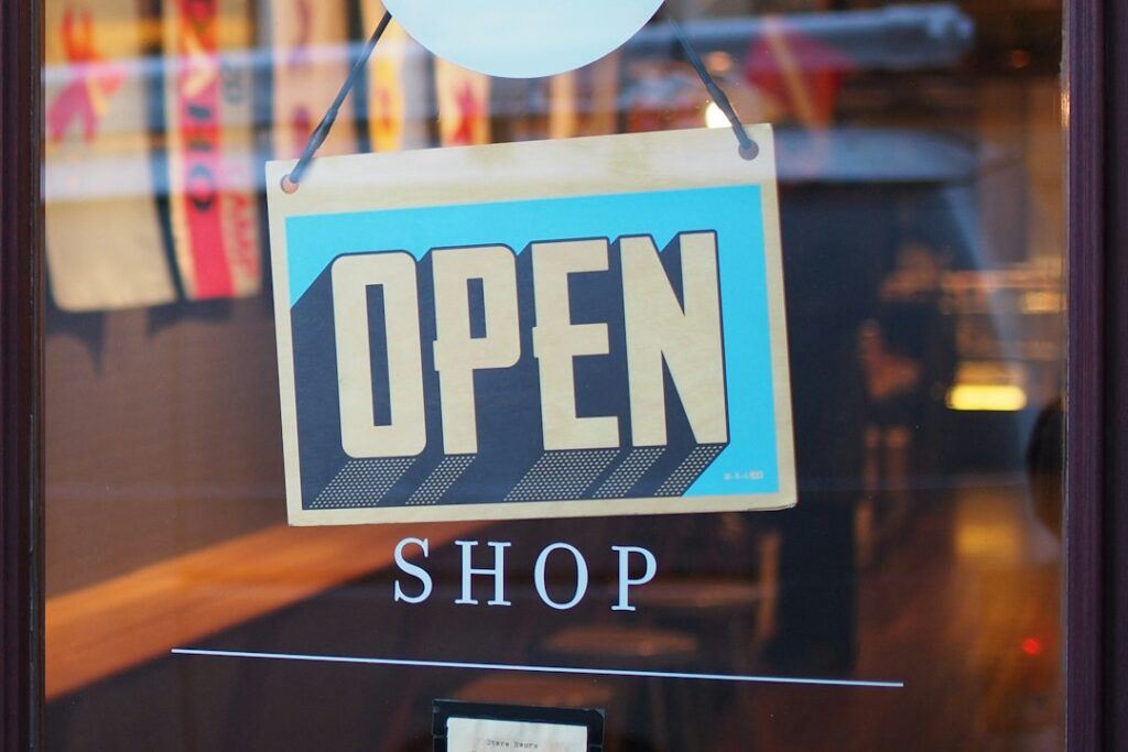 Small business owner standing at the entrance of a local shop with an open sign